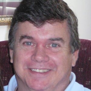 Smiling man with dark hair in a casual setting.